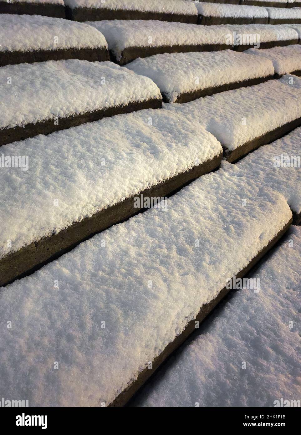 La neve bianca giace in uno strato spesso sui gradini di cemento. Fotografato da un angolo basso e obliquamente Foto Stock