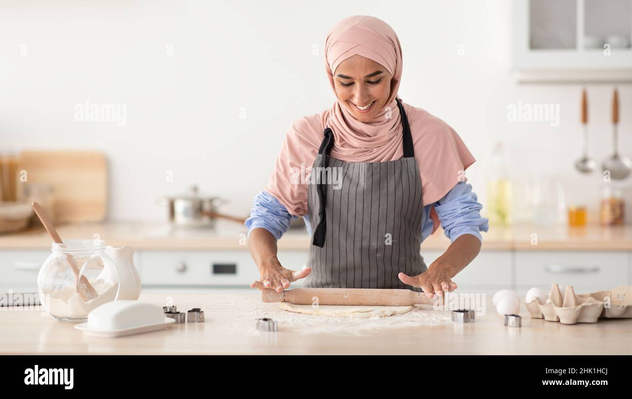 Ritratto di allegra casalinga Islamica che indossa Hijab e Apron cottura in cucina Foto Stock