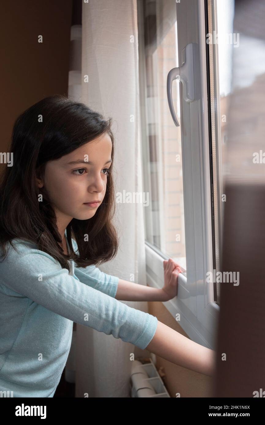 Ragazza che guarda fuori dalla finestra della sua casa, Toledo, Spagna Foto Stock