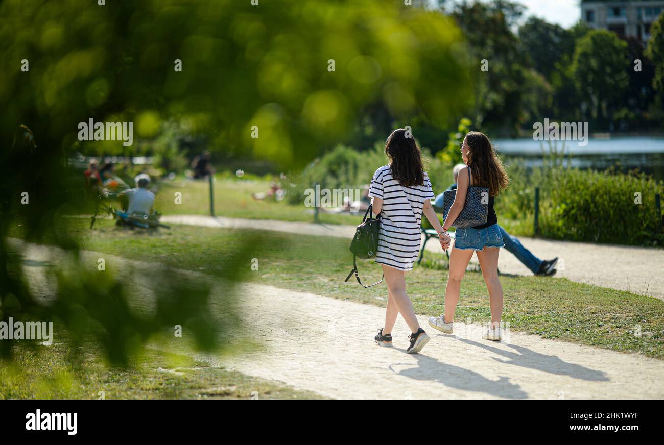 Due giovani ragazze camminano vicino ad un lago nel Bois de Boulogne durante l'estate a Parigi, Francia. Foto Stock