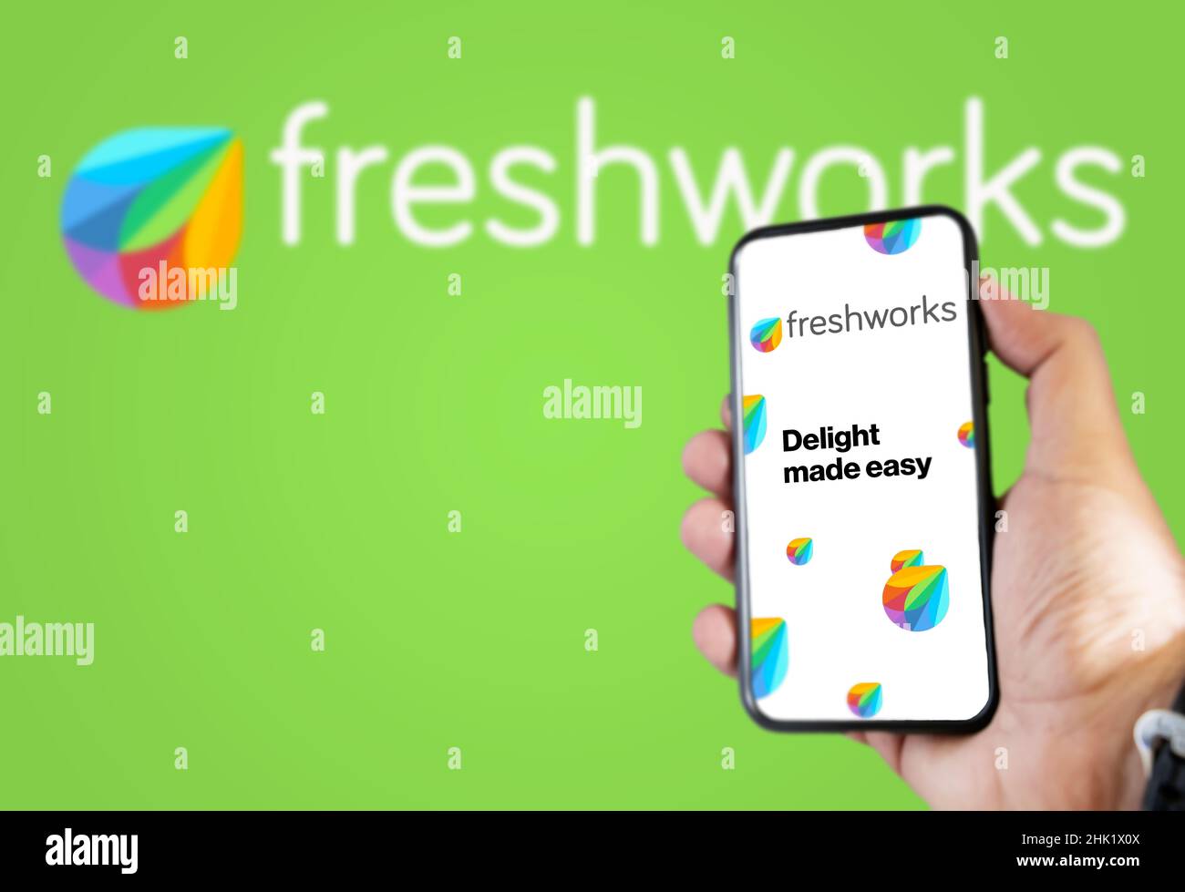 San Francisco, USA, dicembre 2021: Mano che tiene un telefono con l'applicazione mobile Freshworks sullo schermo. Logo Freshworks sfocato su uno sfondo verde Foto Stock