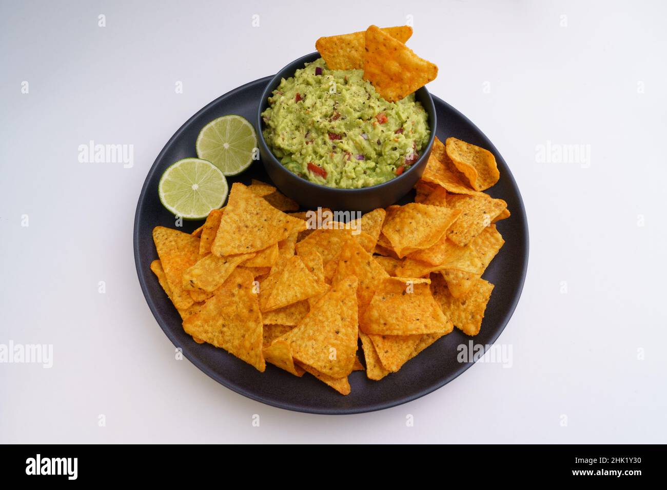Salsa di guacamole e tortilla patatine o nachos in piastra nera isolata su sfondo bianco Foto Stock