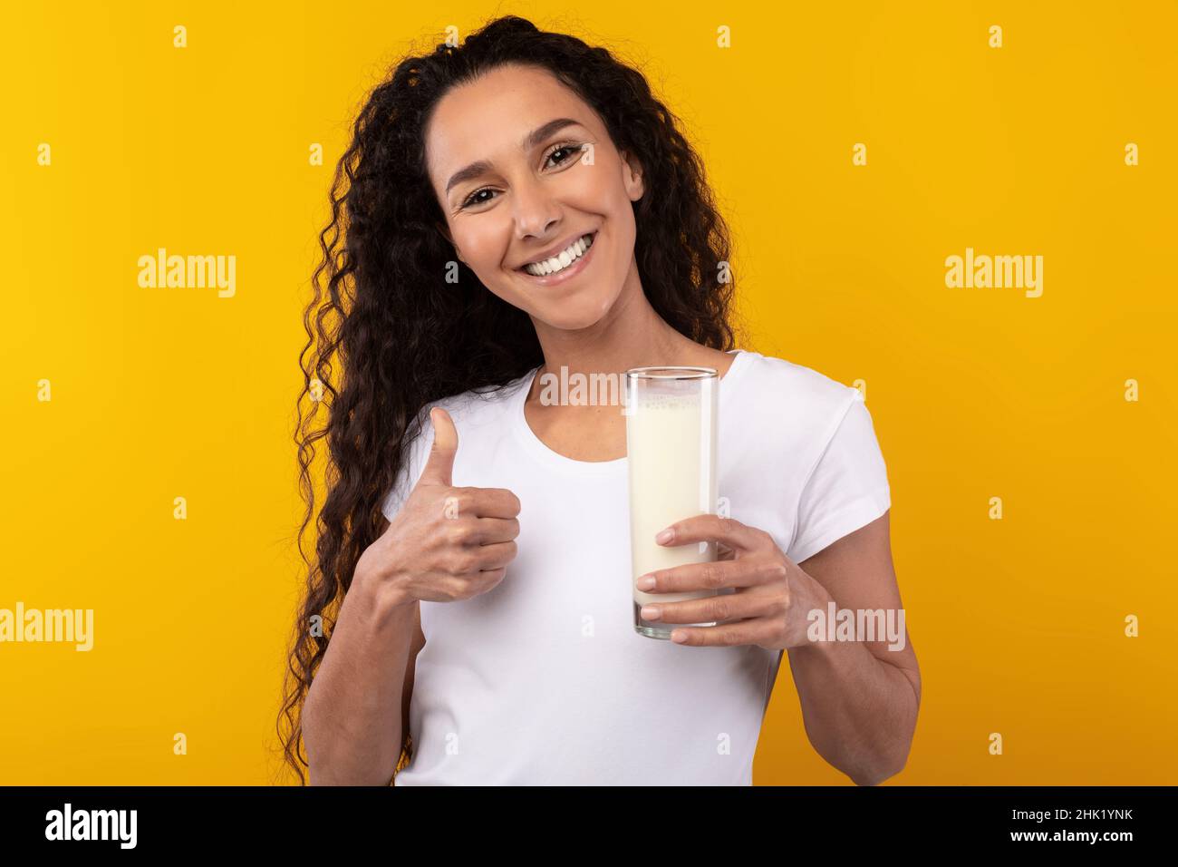 Happy Young Woman Holding Glass of Milk at Studio Foto Stock