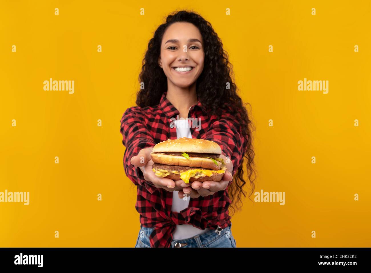 Happy Young Lady Holding e dare Burger allo Studio Foto Stock