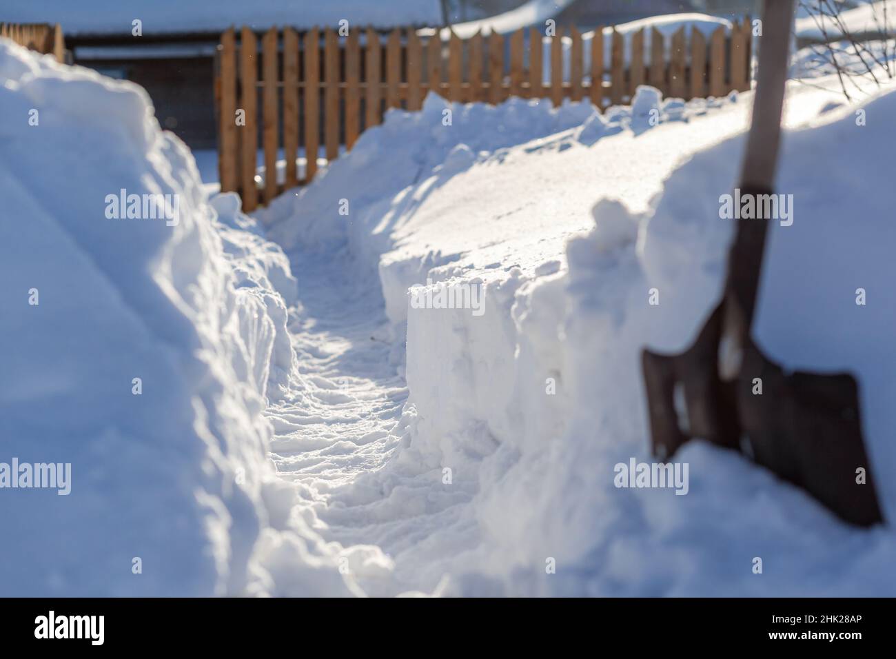 Un uomo ha scavato un passaggio attraverso un sacco di neve. Sgombrare la neve alla casa e recinzione dopo una grande nevicata in inverno. Foto Stock