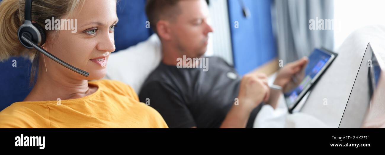 Giovane coppia uomo e donna lavorano da remoto su un computer portatile mentre si trova a letto Foto Stock