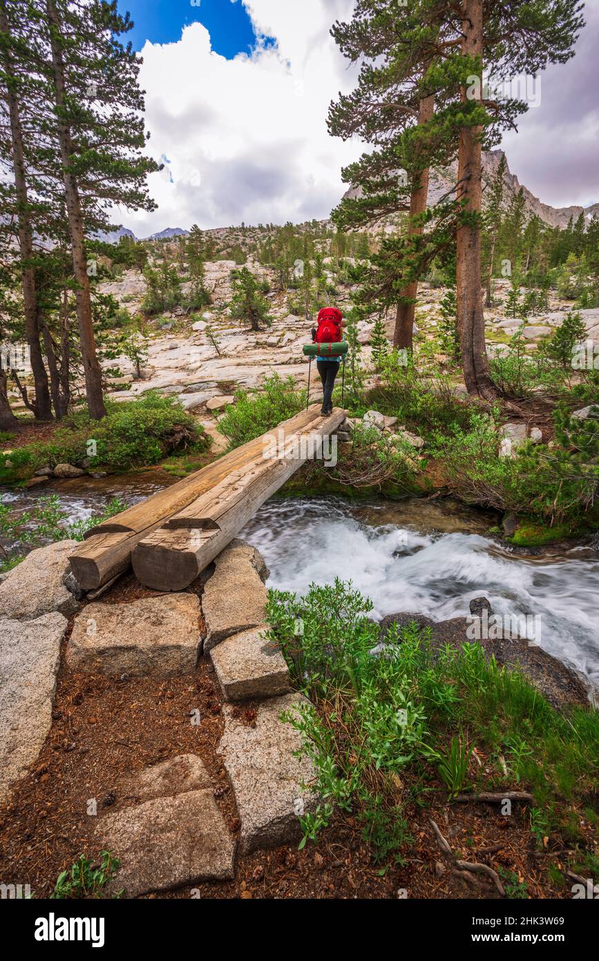 Backpacker che attraversa il torrente nel John Muir Wilderness, Sierra Nevada Mountains, California, USA. Foto Stock