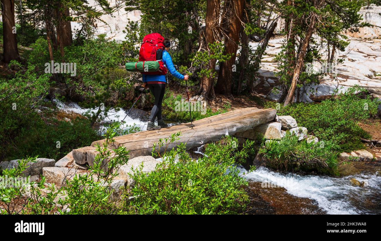 Backpacker attraversando Bishop Creek sul sentiero dei laghi del tesoro, John Muir Wilderness, Sierra Nevada Mountains, California, USA. Foto Stock