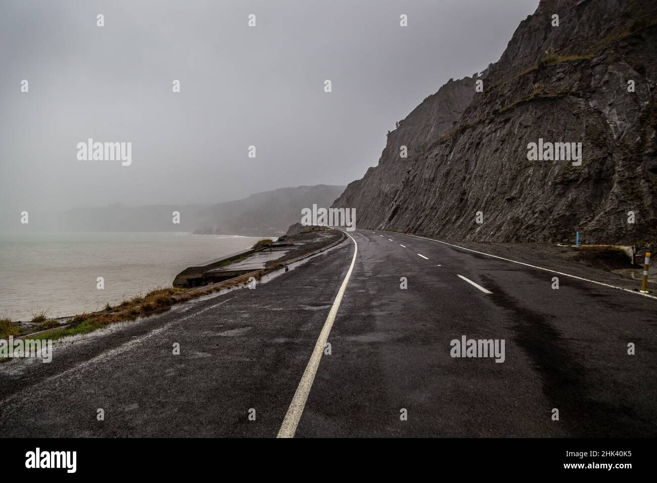 Strada costiera in una giornata di tempesta a Capo Palliser vicino Wellington, Nuova Zelanda. Foto Stock