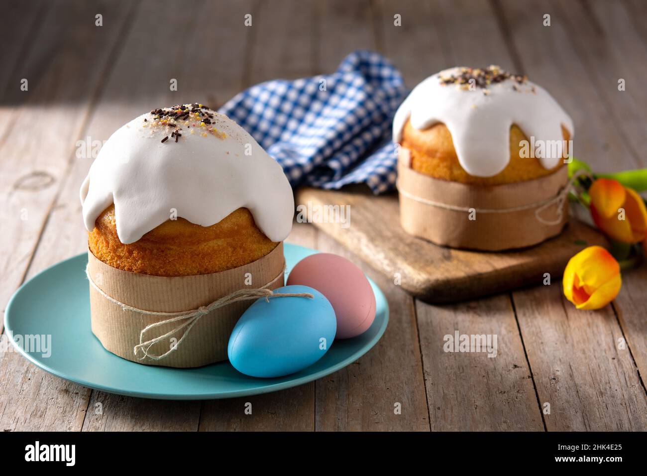 Tradizionale torta pasquale, uova colorate e tulipani su tavola di legno. Foto Stock