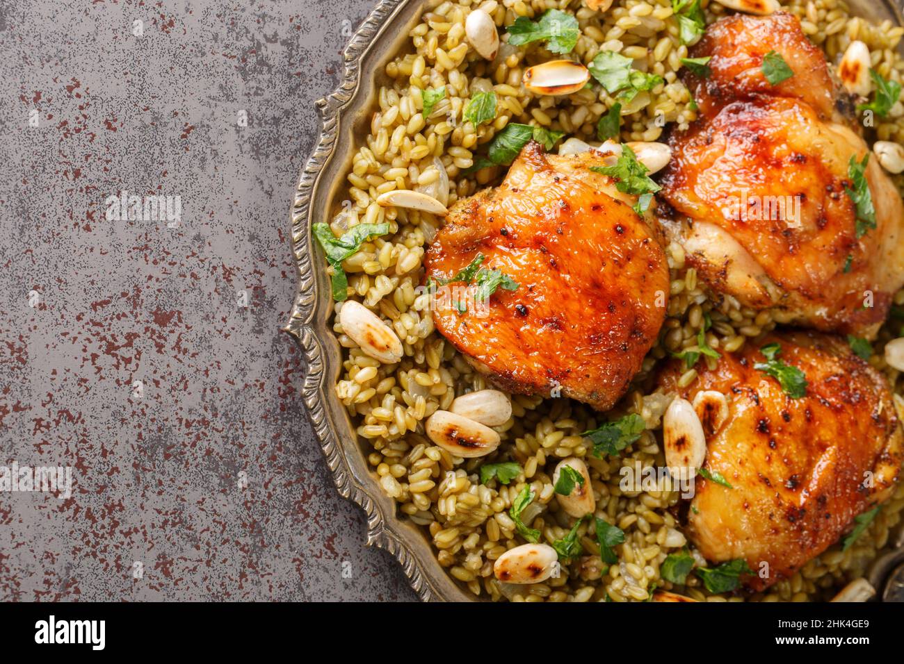 Groats Freekeh con il pollo è un pasto arabo così ben arrotondato primo piano nel piatto sul tavolo. Vista dall'alto orizzontale Foto Stock