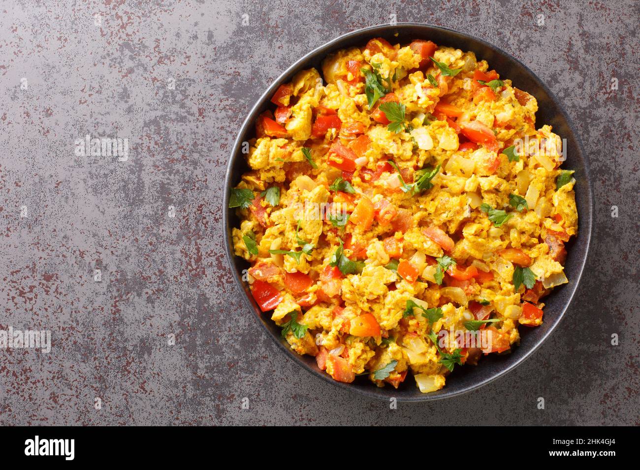 Colazione indiana classica, l'Egg Bhurji è un appetitoso spinning speziato su uova strapazzate primo piano nel piatto sul tavolo. Vista dall'alto orizzontale da abov Foto Stock