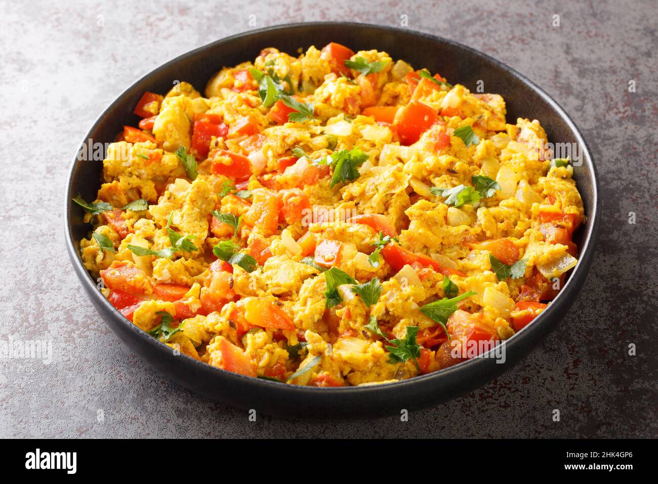 Colazione indiana classica, l'Egg Bhurji è un appetitoso spinning speziato su uova strapazzate primo piano nel piatto sul tavolo. Orizzontale Foto Stock