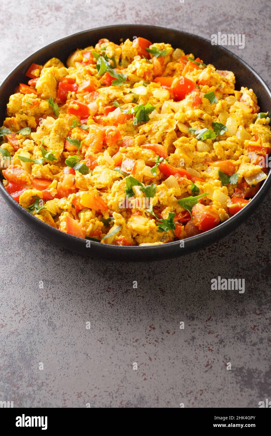 Anda Bhurji è uno stile indiano speziato uova strapazzate primo piano nel piatto sul tavolo. Verticale Foto Stock