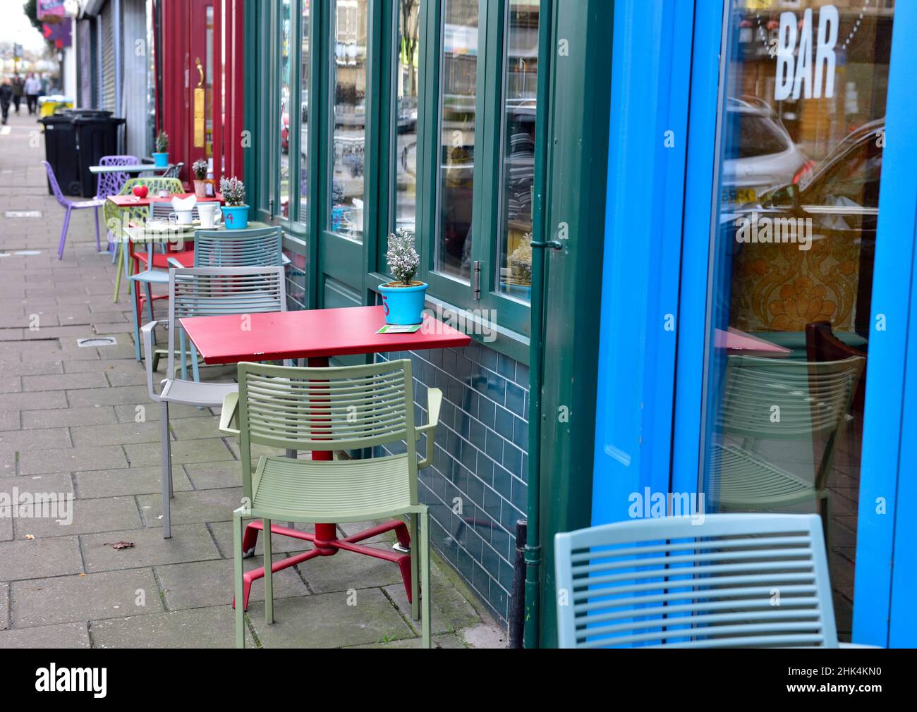 Fila di tavoli e sedie colorati vuoti sul marciapiede all'esterno del bar cafè in attesa dei clienti Foto Stock