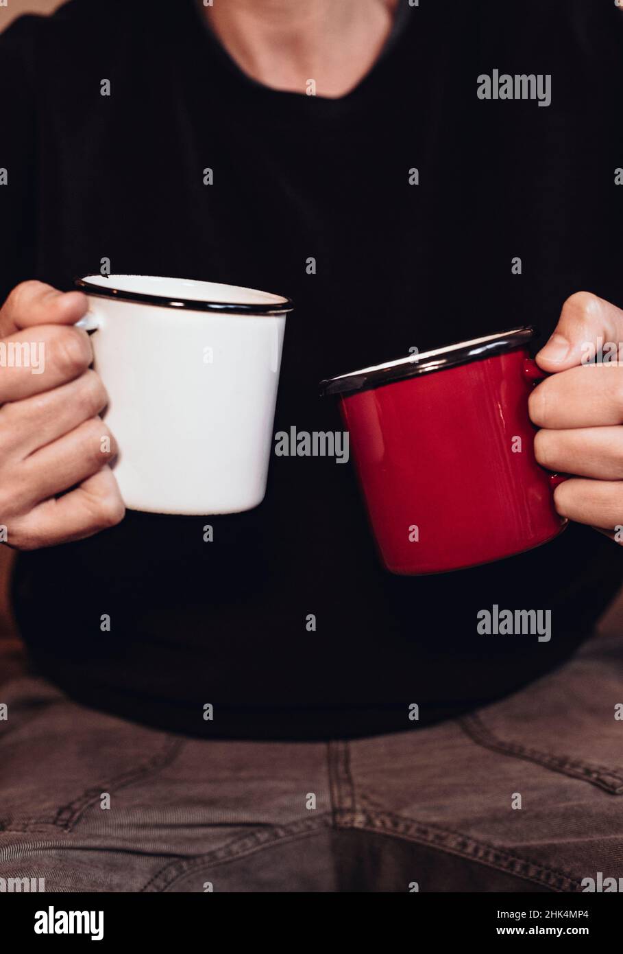 Mani donna vicine che tengono due tazze con sfondo scuro per contenuti promozionali, caffè, cioccolato o tè. Concetto di amicizia Foto Stock