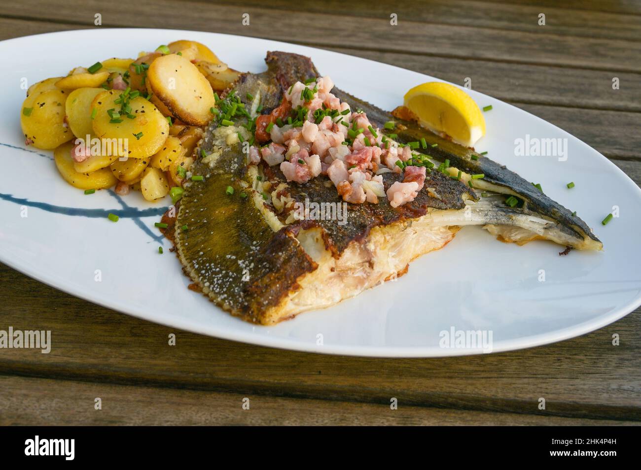 Passera fritta con pancetta e patate su un piatto e un rustico tavolo in legno, fuoco selezionato, stretta profondità di campo Foto Stock