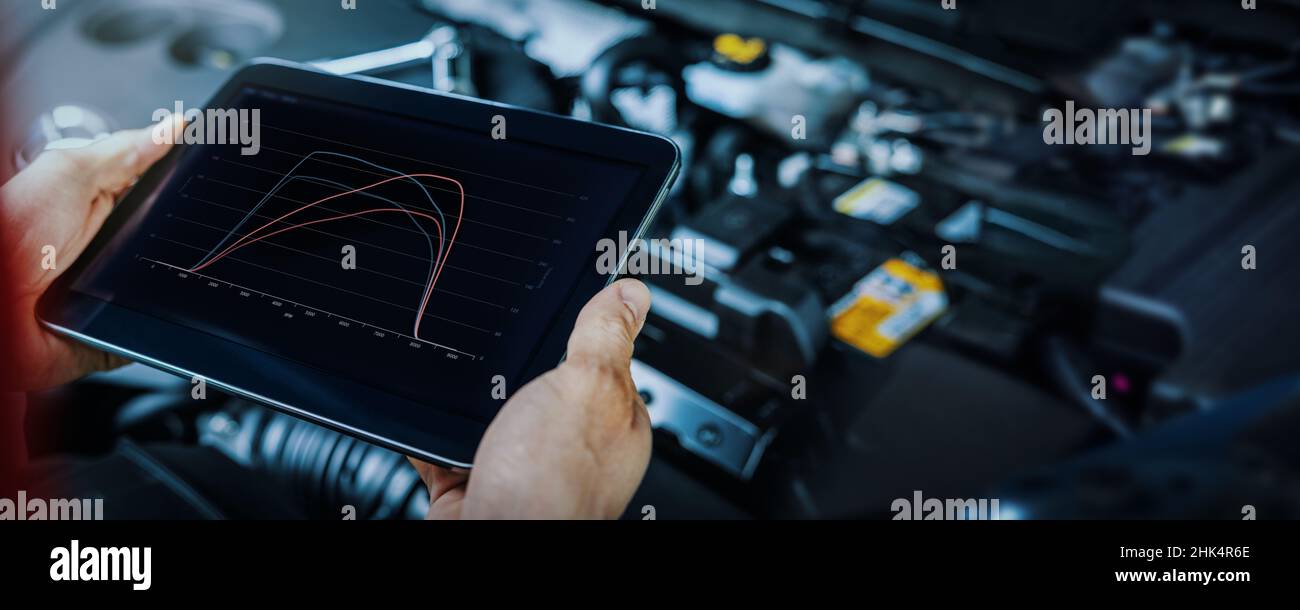 rimappatura e diagnostica dell'ecu del motore dell'auto. meccanico che utilizza un tablet digitale per controllare le prestazioni del veicolo dopo l'ottimizzazione Foto Stock