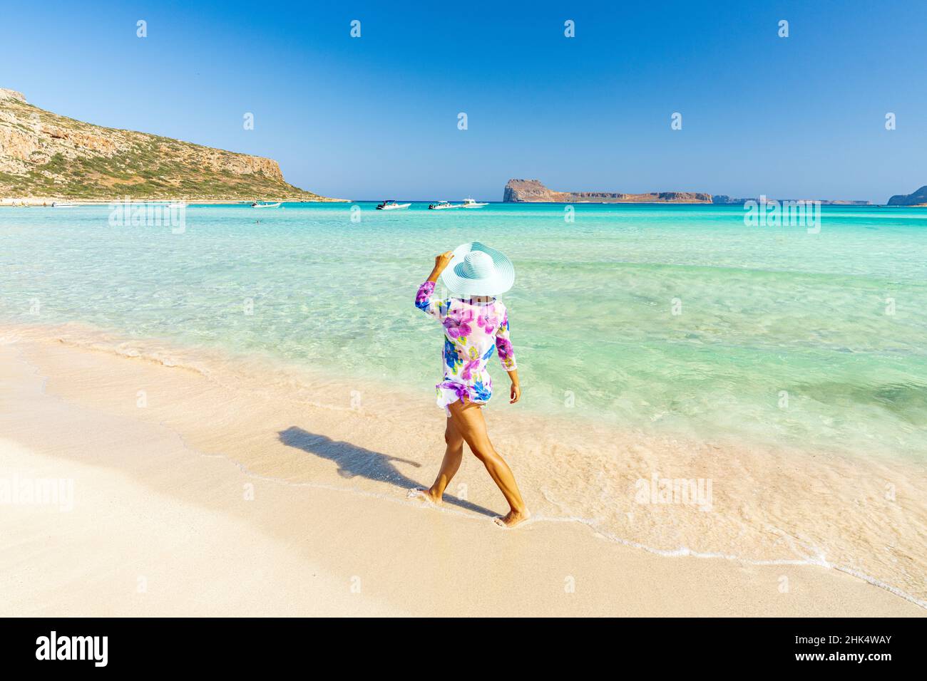Bella donna con cappello di sole a piedi su idilliaca spiaggia vuota, Creta, Isole Greche, Grecia, Europa Foto Stock