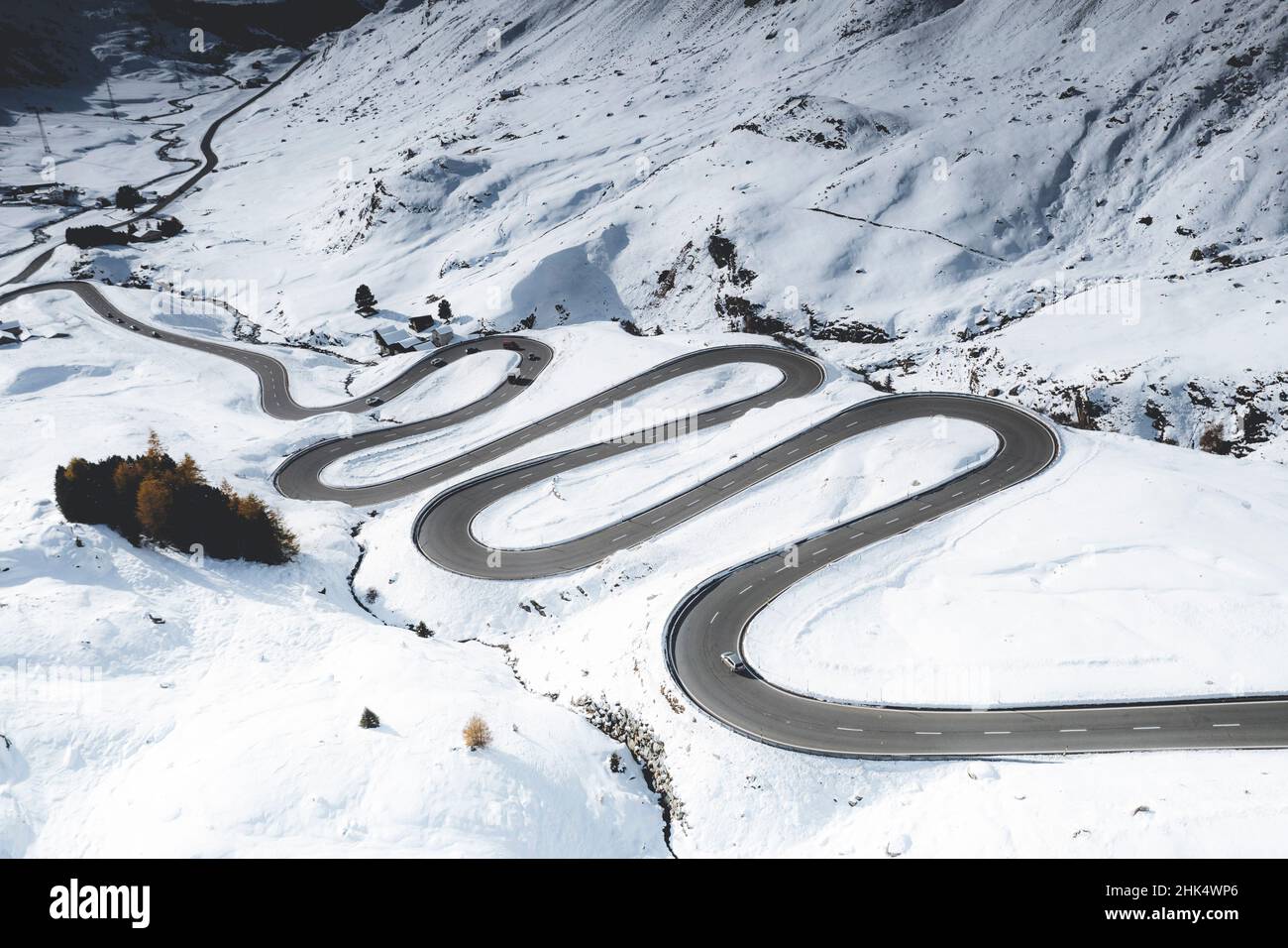 Auto che viaggia su curve di strada tortuosa nella neve, Passo Julier, distretto di Albula, Engadina, cantone di Graubunden, Svizzera, Europa Foto Stock