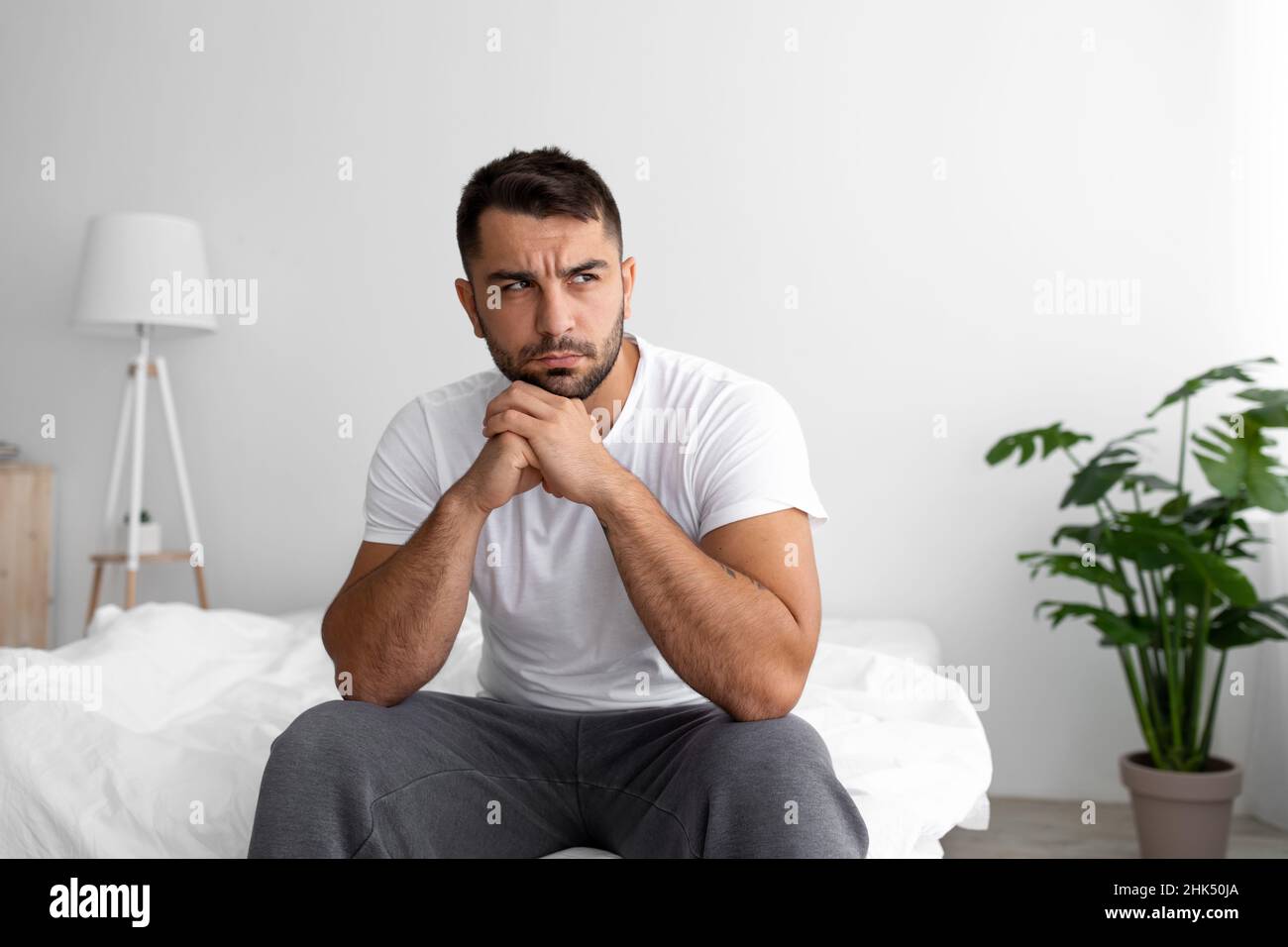 Disperazione triste giovane muscoloso caucasico uomo seduto a letto pensando, risolvere problemi, soffrendo di dolore e cattive notizie Foto Stock