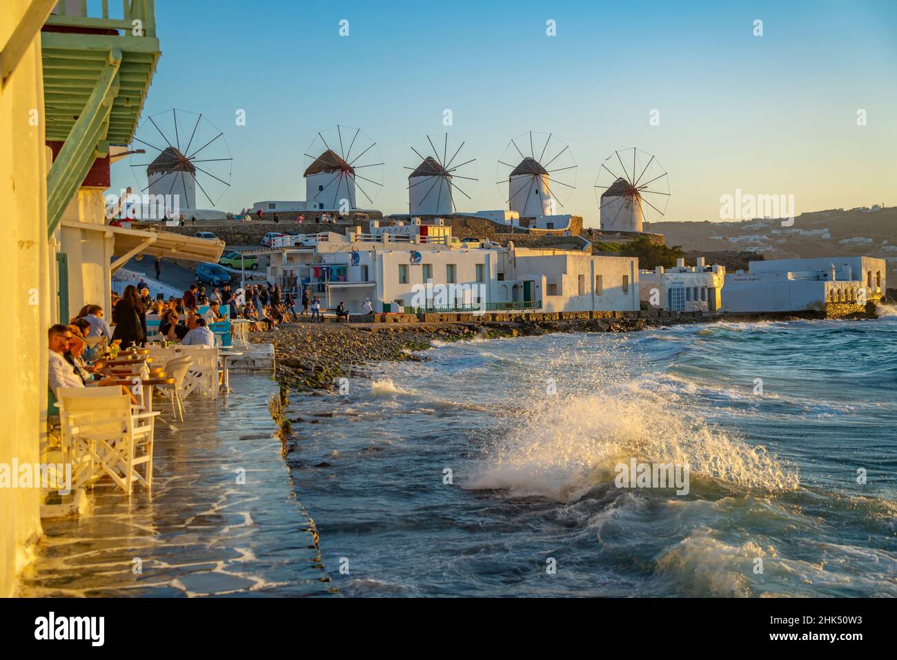 Vista dei mulini a vento e delle onde che si infrangono nella città di Mykonos al tramonto, Mykonos, Isole Cicladi, Isole Greche, Mar Egeo, Grecia, Europa Foto Stock