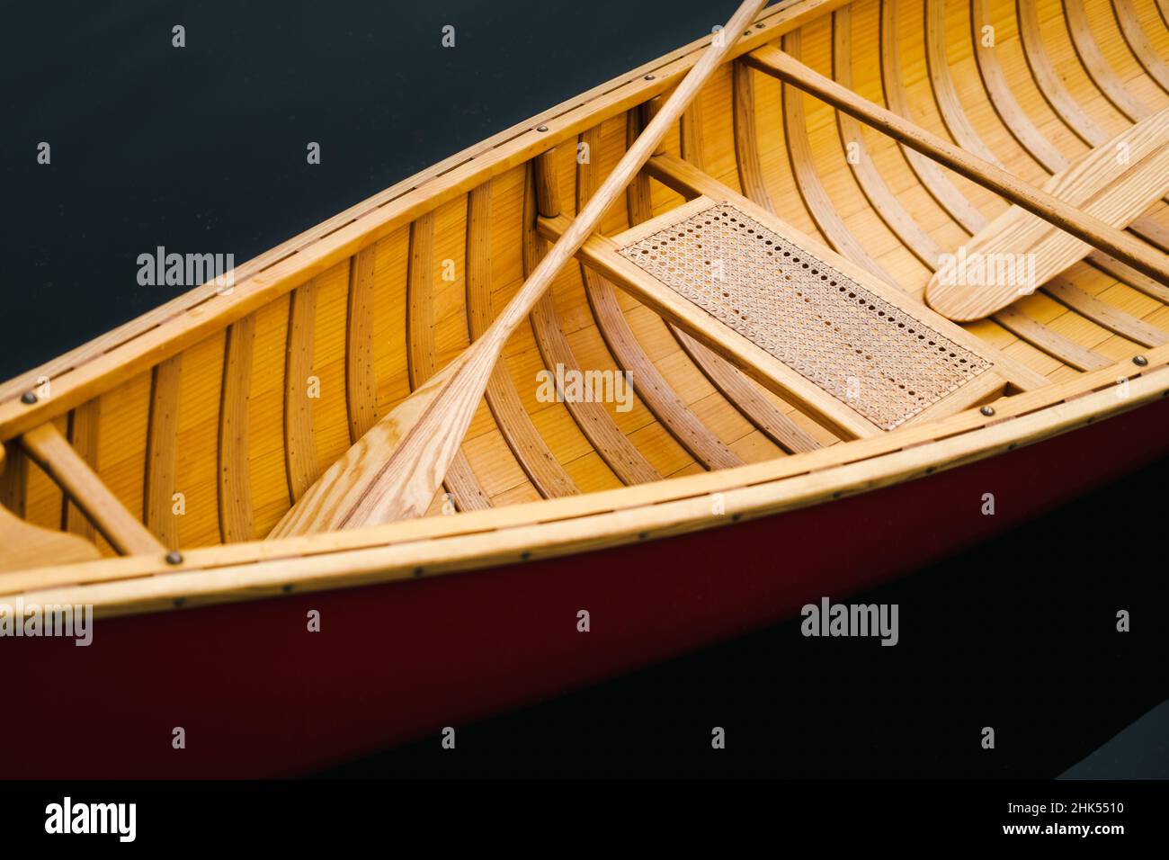 Dettagli di una bella barca in canoa di legno sull'acqua. Pagaie e posto a sedere di una barca galleggiante su acqua scura, nessuna gente Foto Stock