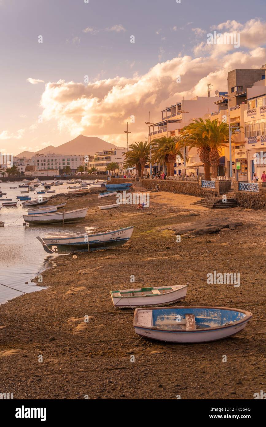 Vista delle barche sulla spiaggia a Baha de Arrecife Marina circondato da negozi, bar e ristoranti al tramonto, Arrecife, Lanzarote, Isole Canarie, Spagna Foto Stock