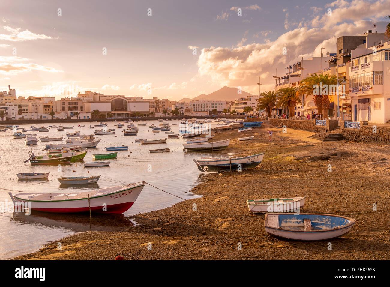 Vista delle barche sulla spiaggia a Baha de Arrecife Marina circondato da negozi, bar e ristoranti al tramonto, Arrecife, Lanzarote, Isole Canarie, Spagna Foto Stock