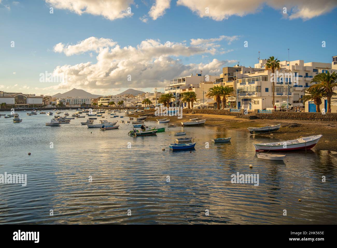 Vista delle barche sulla spiaggia a Baha de Arrecife Marina circondato da negozi, bar e ristoranti al tramonto, Arrecife, Lanzarote, Isole Canarie, Spagna Foto Stock