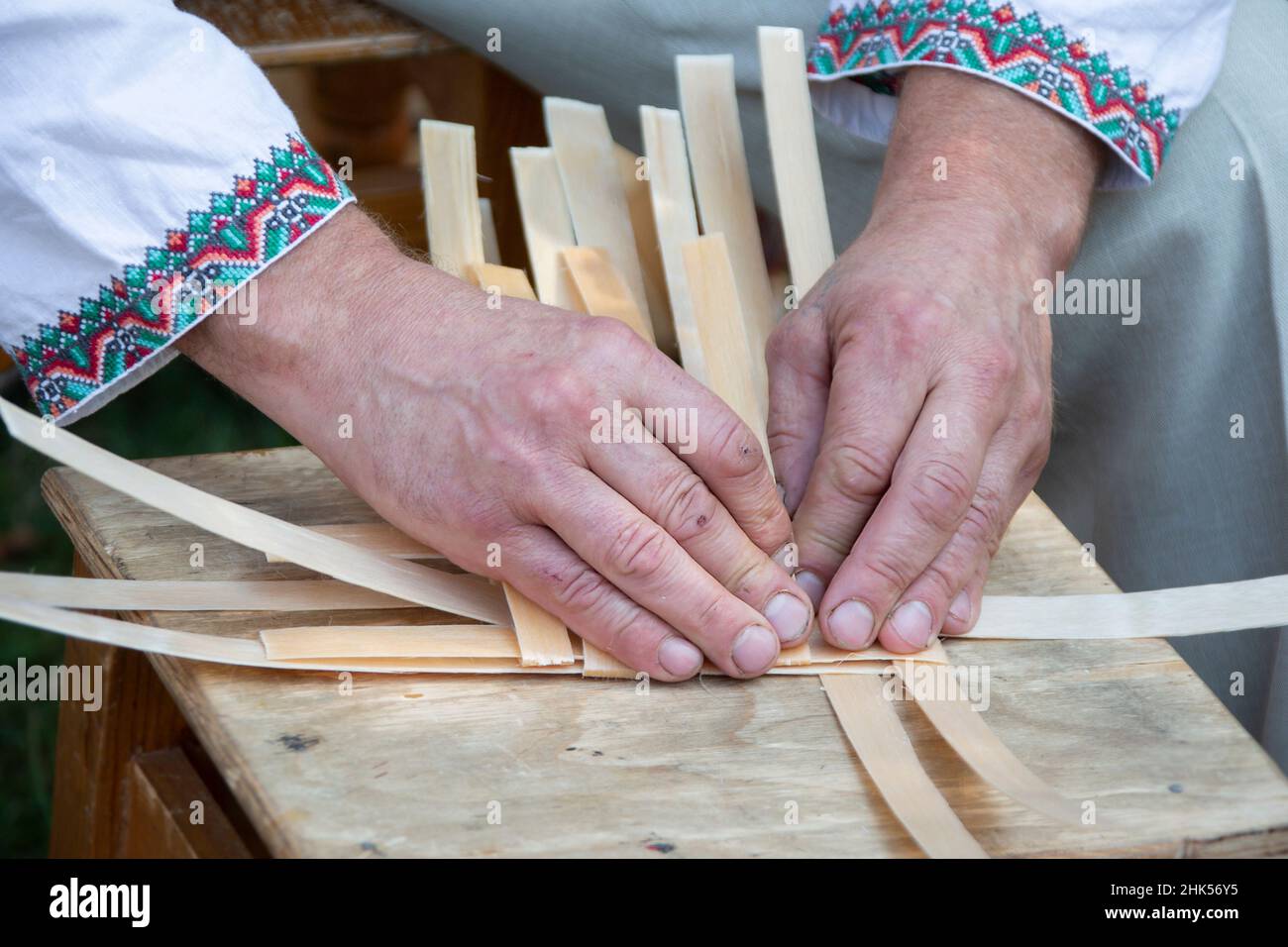 Le mani del maestro tessono un cesto di viti di betulla. Foto Stock