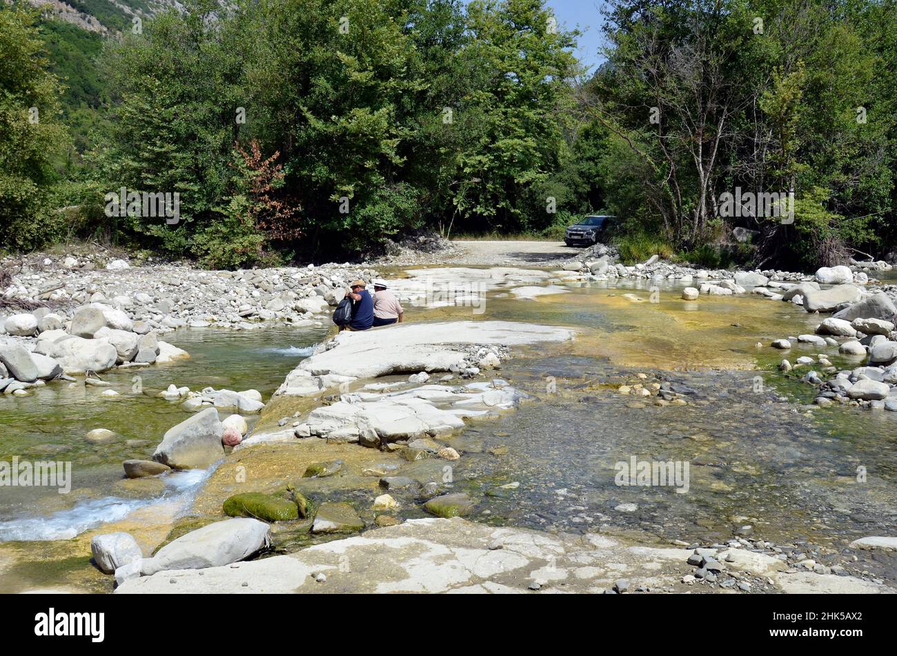 Plaka, Grecia - 30 giugno 2021: Coppia di anziani sconosciuti sulla riva del fiume dove la strada divenne impraticabile nel Parco Nazionale di Tzoumerka- Peristeri- A. Foto Stock