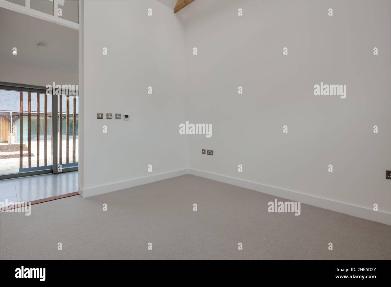 Trumpington, Cambridgeshire - Maggio 04 2017: Ingresso vuoto dipinto di bianco sala open space soggiorno in nuova casa con porta aperta e grandi porte patio Foto Stock