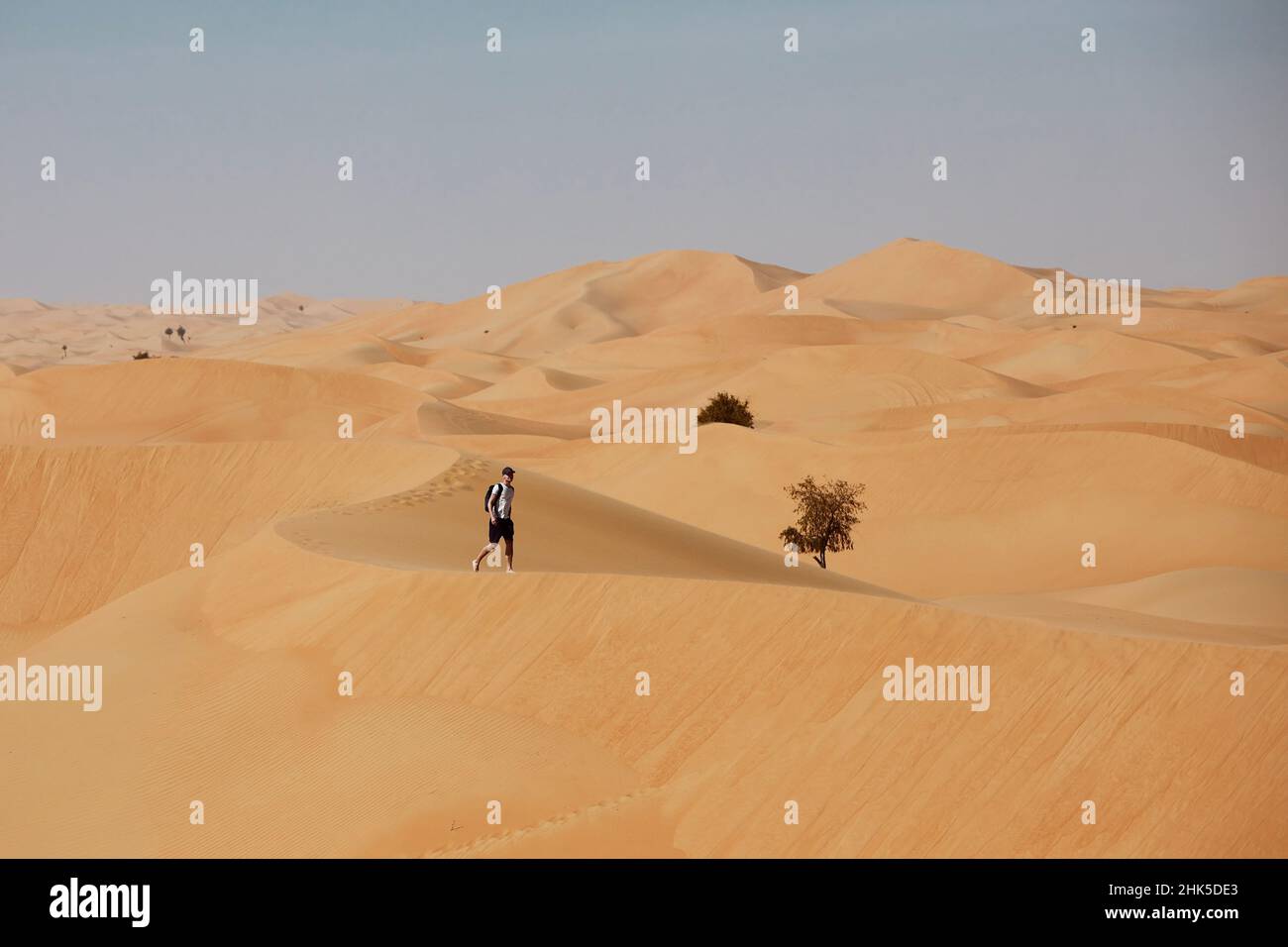 Uomo che cammina sulla duna di sabbia. Turista in paesaggio desertico. Abu Dhabi, Emirati Arabi Uniti Foto Stock