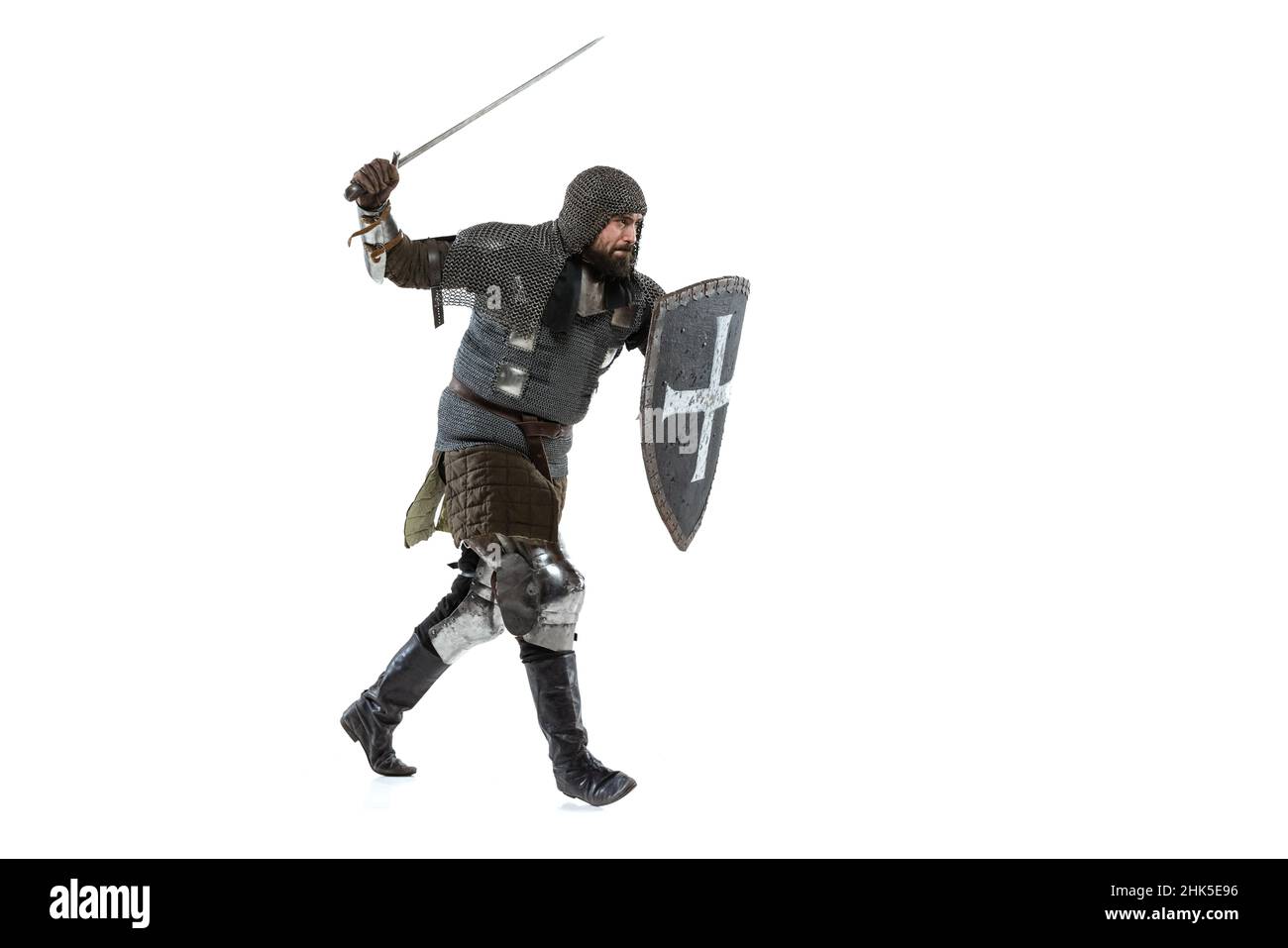 Ritratto di coraggioso guerriero medievale, cavaliere in speciale cappotto di posta attaccando con la spada isolato su bianco studio backgronde Foto Stock