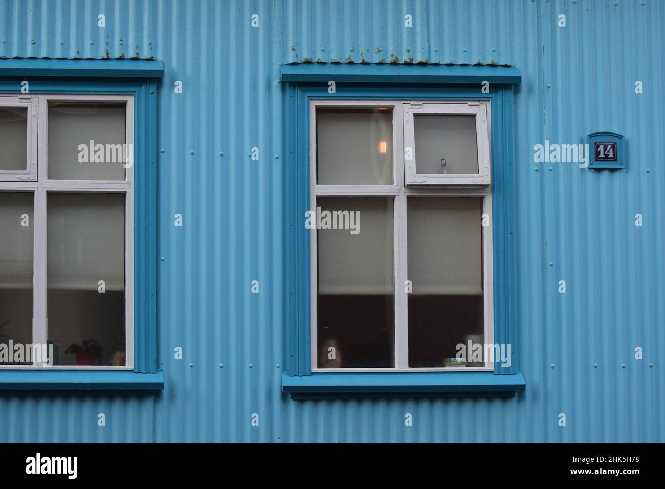 Le finestre di una tradizionale casa in lamiera di Reykjavik dipinta di blu brillante Foto Stock