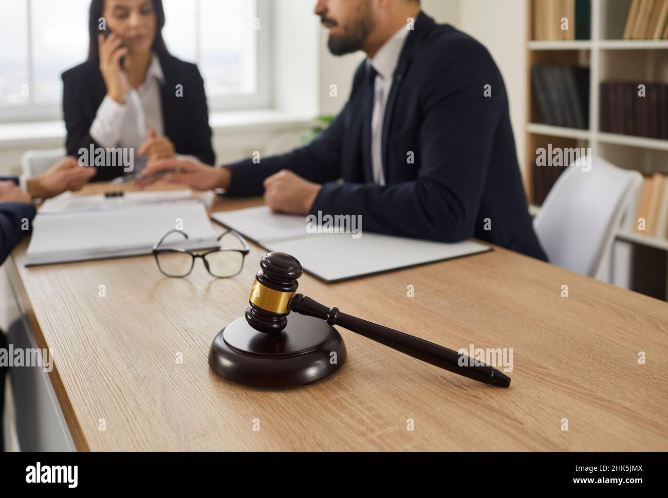 Mazzuolo del giudice sul tavolo, e avvocato che dà consulenza legale ai clienti in background Foto Stock