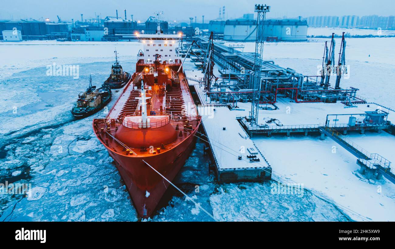 Spedizione di olio su grande petroliera rossa dal sistema di pompaggio terminale su acqua coperta con strato spesso di ghiaccio rotto in vista aerea ghiacciata invernale Foto Stock