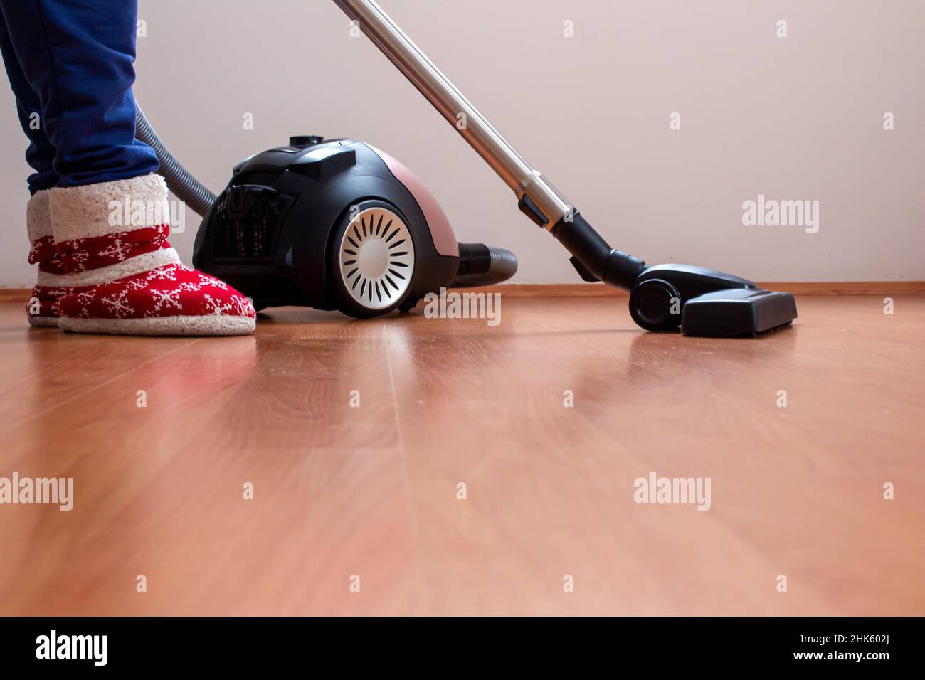 Donna che usa un aspirapolvere per pulire il pavimento in parquet. Sta  pulendo la casa dove c'è polvere in eccesso Foto stock - Alamy