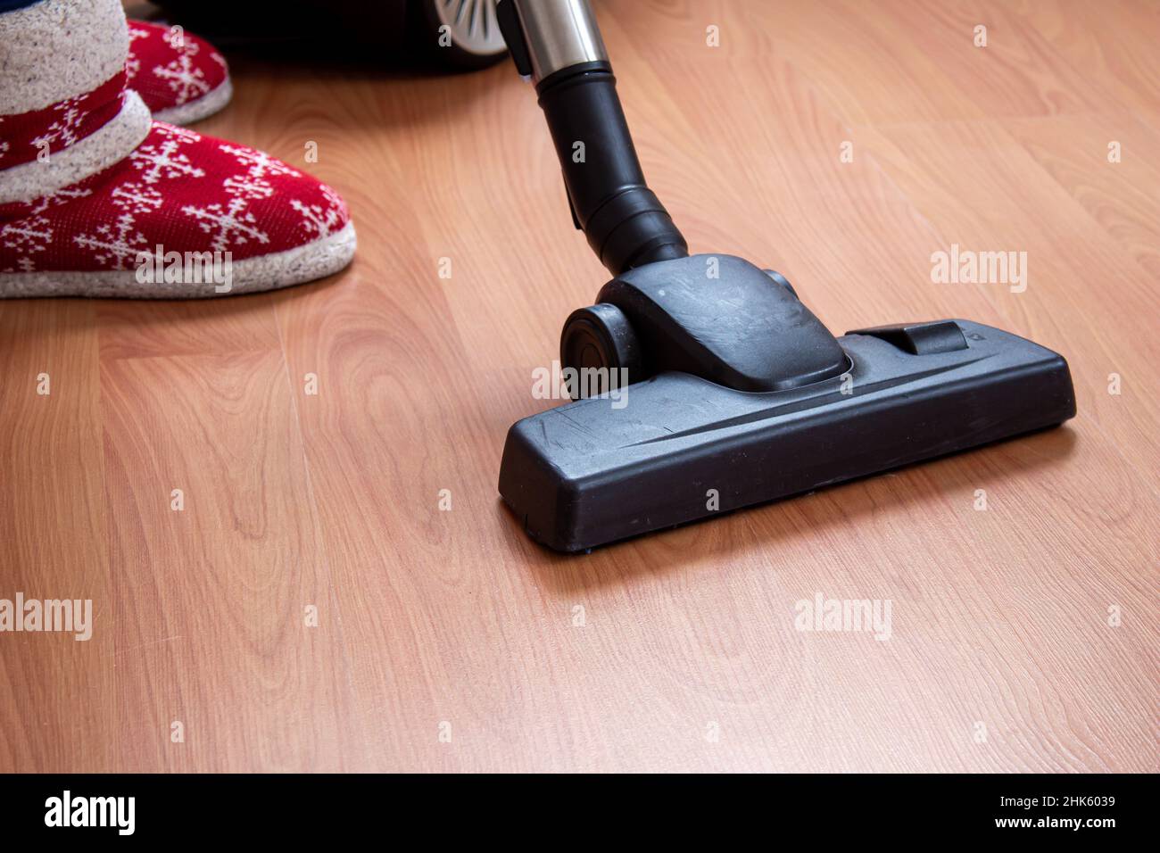 Donna che usa un aspirapolvere per pulire il pavimento in parquet