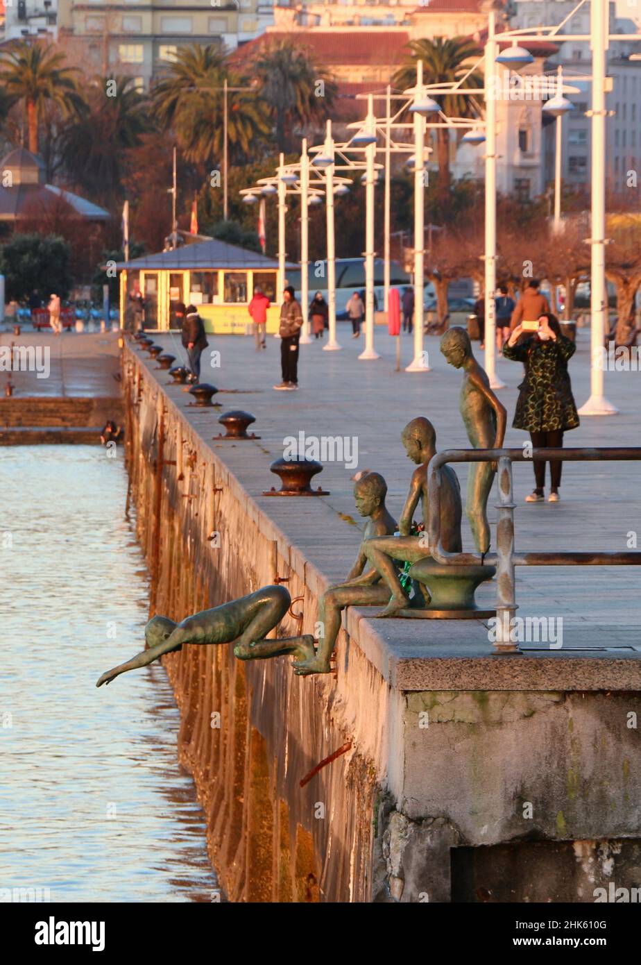 Una donna che fa una foto del Monumento ai beachcombers di Jose Cobo statue di bronzo di quattro ragazzi con il suo telefono cellulare Bay di Santander Spagna Foto Stock