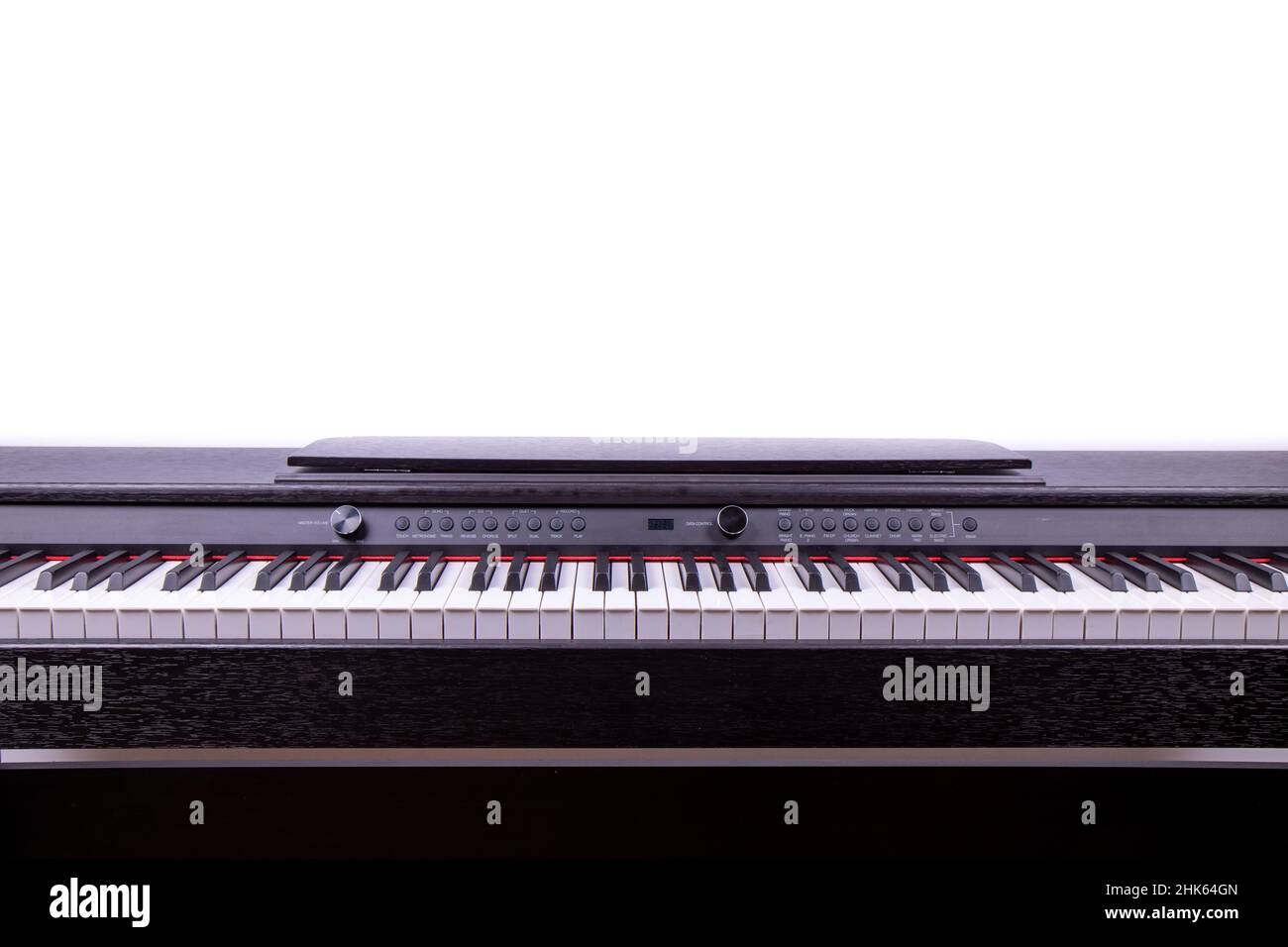 Un pianoforte elettrico su sfondo bianco, che mostra i moderni tasti piano su una parete bianca Foto Stock
