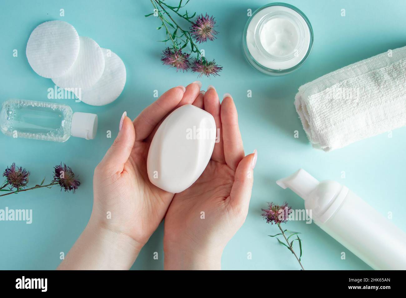 Sapone per mani femminili. Prodotti cosmetici su sfondo blu. Accessori spa, cura del corpo. Concetto di benessere. Foto Stock