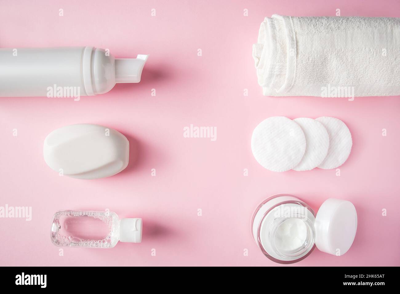 Prodotti cosmetici su sfondo rosa. Bottiglie bianche di crema e lozione. Accessori spa, cura del corpo. Concetto di benessere. Foto Stock