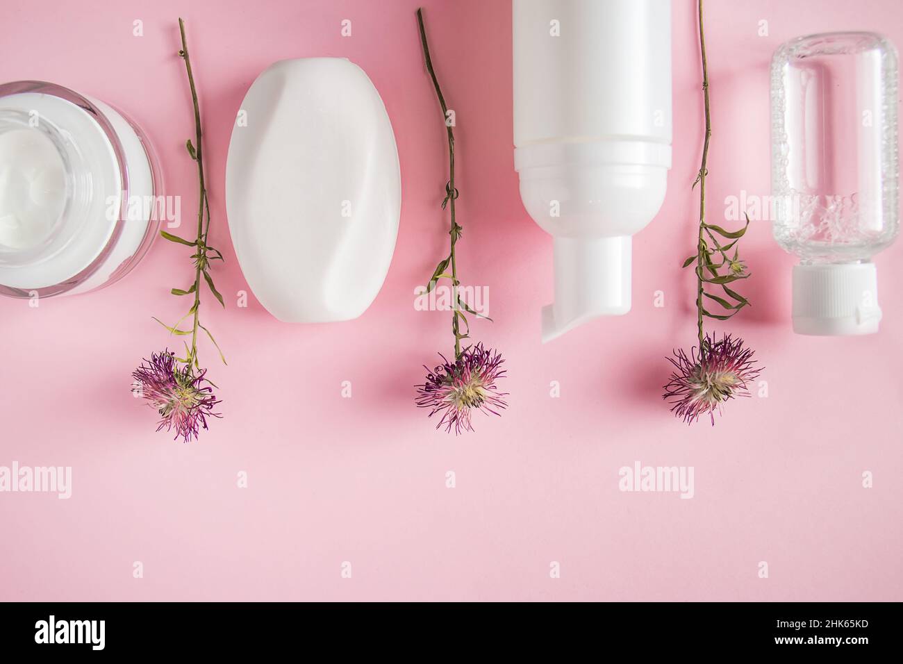 Prodotti cosmetici su sfondo rosa. Bottiglie bianche di crema e lozione. Accessori spa, cura del corpo. Concetto di benessere. Foto Stock