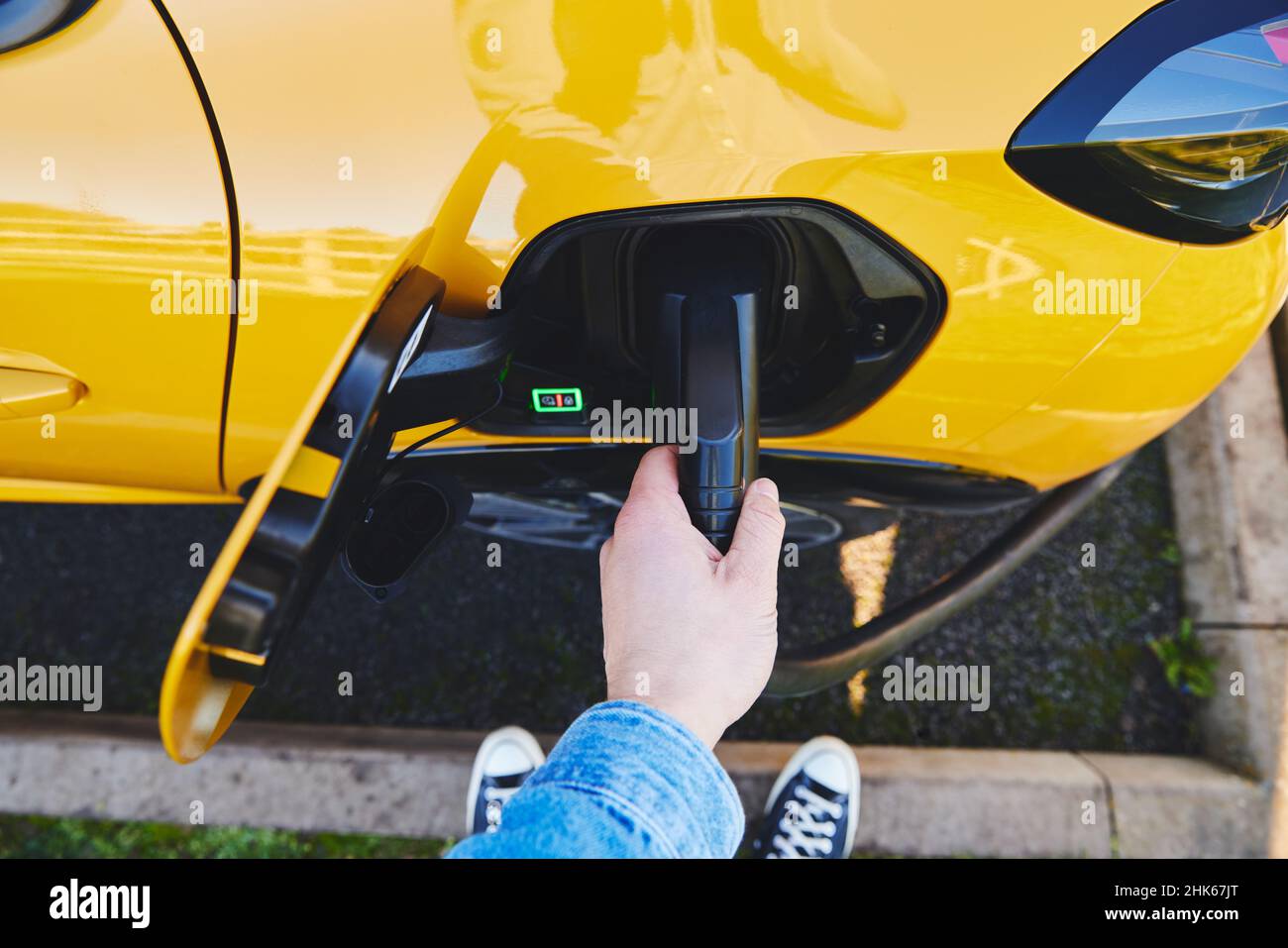 POV dell'uomo che collega l'auto elettrica solo a mano Foto Stock