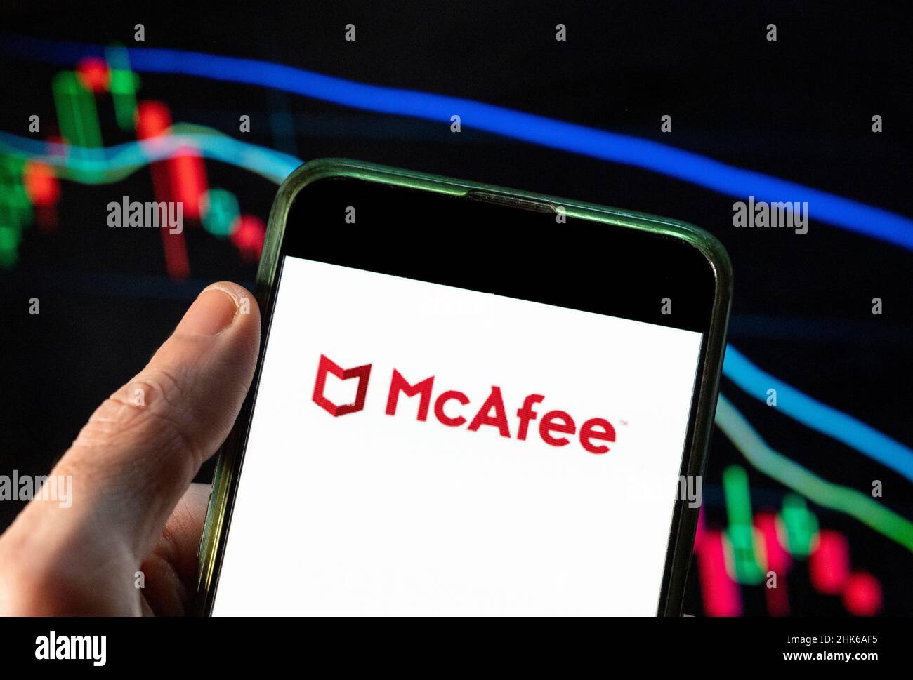 Cina. 4th Dic 2021. In questa illustrazione della foto, il logo McAfee della società americana globale di software per la sicurezza informatica è visualizzato su uno smartphone con un grafico dell'indice delle borse economiche sullo sfondo. (Credit Image: © Budrul Chukrut/SOPA Images via ZUMA Press Wire) Foto Stock