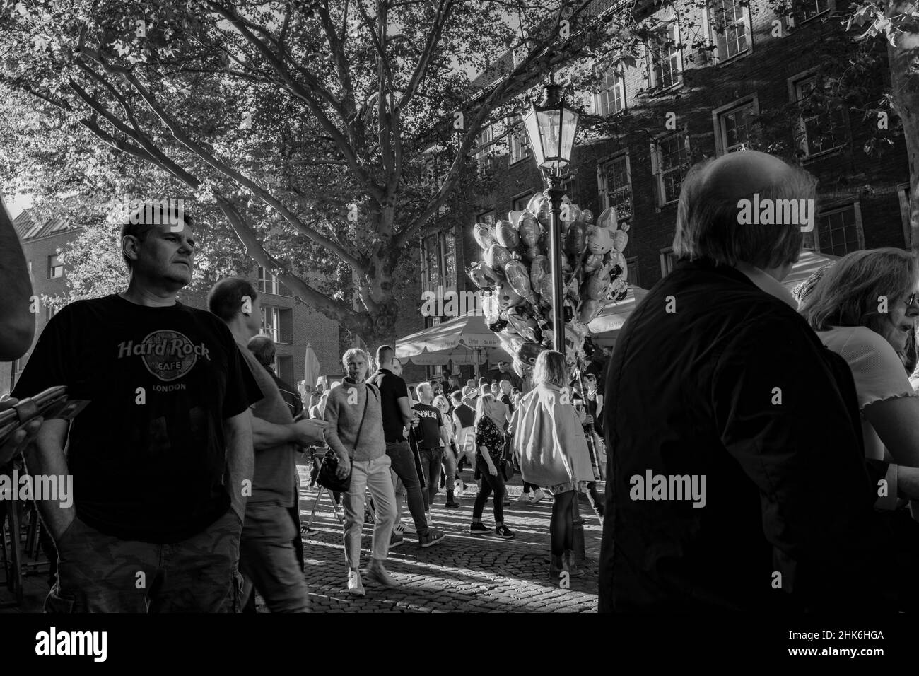 I visitatori della Altstadt hanno pochi Altbier fuori dalla birreria 'Uerige' mentre un uomo vestito come un camino passeggiando con palloncini di elio a Düsseldorf, NRW, Germania Foto Stock