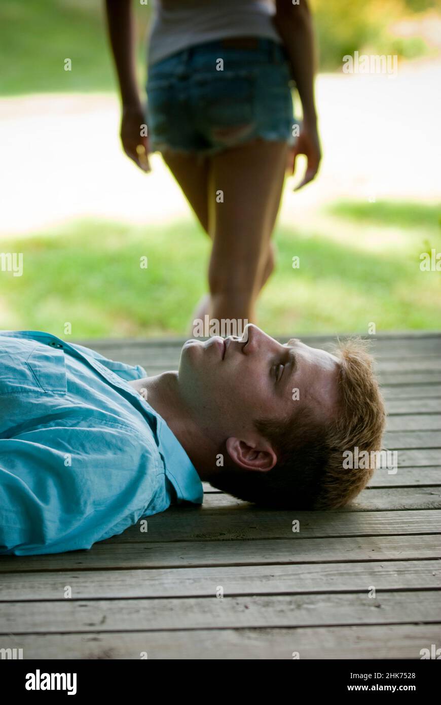 Giovane uomo che si stese sul portico con la donna in piedi sul retro Foto Stock