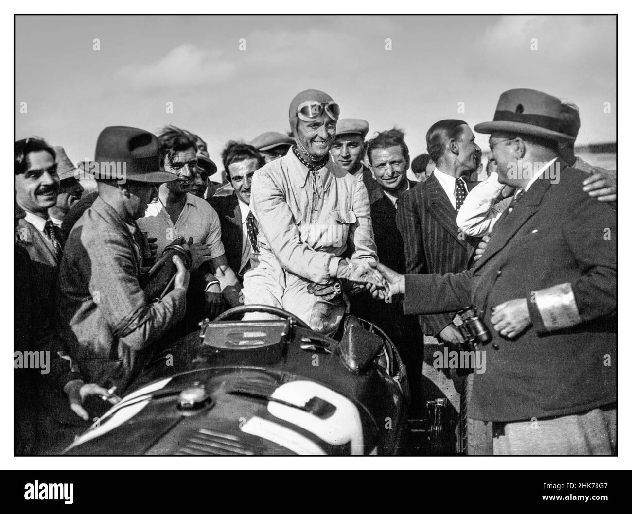 D'epoca 1930s Grand Prix Francia Louis Chiron in un Alfa Romeo con le congratulazioni dell'impiegato del circuito dopo aver vinto il Gran Premio di Francia 1934 1 luglio 1934 XXVIII Grand Prix de l'Automobile Club de France Autodrome de Montlhéry Foto Stock